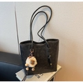 Detalle de un bolso tote negro texturizado con un colgante de león y logo de la marca - Negro con colgante