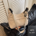 Light grey nylon dumpling crossbody bag with adjustable strap on black leather sofa - Off White