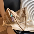Detalle del bolso acolchado caqui con correa anudada y un amuleto tejido de colores vivos - Caqui