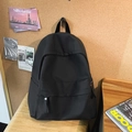 Zaino nero minimalista in nylon per studenti mostrato in un ambiente accogliente da studio - Nero