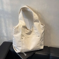 Borsa tote minimalista in velluto a coste crema con tasca frontale su divano in pelle nera - Bianco