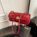 Retro red faux leather baguette shoulder bag with gold clasp held in hand - Red