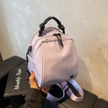Lavender nylon mini backpack with black zippers and woven handle in a handheld view - Taro