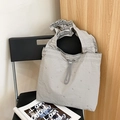 Detail of silver rivets and cloud-pleated handle on a light gray nylon tote bag - Gray