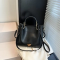 Sac seau noir minimaliste avec poignée ronde et détails dorés sur un fond élégant - Noir