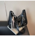 Detail of a black half-moon shoulder bag with an adjustable strap and pink woven charm - With Pendant / Black