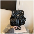 Detail of black quilted leather backpack featuring silver twist lock and chain accents - Black