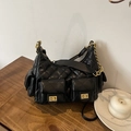 Sac bandoulière matelassé noir avec détails dorés et chaîne sur une table en bois - Noir