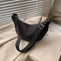 Minimalist black nylon crescent bag with adjustable wide strap shown on beige blazer - Black