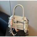 Detalle de un bolso gris claro con correas decorativas y hebillas plateadas - Con Colgante / Gris