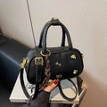 Elegant black leather bowling bag with gold dog charm and woven strap detail - With Pendant / Black
