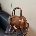 Brown faux leather bowling bag with gold charms, crossbody strap, and plaid scarf detail - With Pendant / Coffee