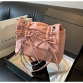 Primer plano del bolso plisado rosa con lazos decorativos y cadena plateada - Rosa