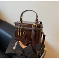 Detail der glänzenden schokoladenbraunen Box-Tasche mit goldenen Doppelreißverschlüssen - Kaffeebraun