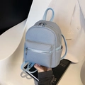 Light blue mini backpack with woven texture and silver zippers on a white chair - Blue