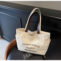 Detail of off-white canvas tote with brown handles and side pockets for extra storage - Off White