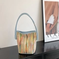 Colorful striped woven bucket bag with light blue leather handle on a glossy surface - Blue