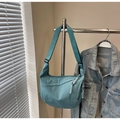 Detailed view of the teal nylon crescent bag showing woven zipper pulls and wide strap - Blue