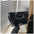 Detail einer schwarzen glänzenden Beuteltasche mit weißen Kontrastnähten und ovalem Griff - Schwarz