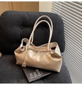 Detalle del bolso tote de cuero crema con hebilla metálica y etiqueta en sofá de pana - Blanco Perlado