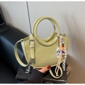 Detail of avocado green bucket bag featuring a circular handle and colorful beaded charm - With Charm / Green