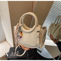 Close-up of creamy white bucket bag with silk scarf and colorful beaded charm detail - With Charm / Off White