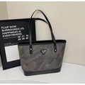 Detalle del bolso tote gris texturizado con asas negras y logotipo triangular metálico - Marrón Oscuro