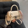 Chique beige mini vierkante tas met tennisracket bedel en koord op een zwarte stoel - Crèmewit Met Hanger