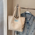 Borsa tote minimalista in tela beige con tasca frontale e logo blu su gruccia - Beige