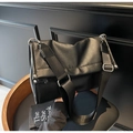 Close-up of black pebbled leather tote bag with adjustable wide fabric shoulder strap - Black PU