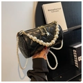 Detalle de bolso cilíndrico negro acolchado con cadenas de perlas y colgante de estrella - Correa de Hombro Larga de Perlas / Negro