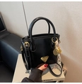 Détail du mini sac seau en similicuir noir brillant avec accessoires dorés et pendentif - Avec Pendentif / Noir