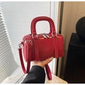 Primer plano de un bolso Boston rojo brillante en cuero pulido con herrajes plateados - Rojo
