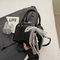 Elegant black bowling handbag with lace bow and racket charm detail on grey suit - Black with Pendant