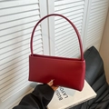 Minimalist dark red baguette bag with sleek handle shown in a fashion lifestyle setting - Red