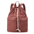 Detail of water-resistant nylon drawstring backpack in rust red with white cotton cords - Berry Red