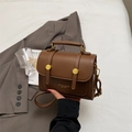Brown leather crossbody messenger bag with gold hardware and top handle shown in lifestyle - Brown