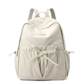 Close-up of cream nylon backpack featuring bow detail and drawstring side pockets - Bone White