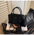 Detalle del bolso de cuero pulido negro con marca de texto blanco y diseño de correa anudada - Negro