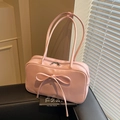 Glossy pink bow shoulder bag in Boston style placed on a black leather seat - Pink