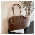 Detailed view of dark brown tote bag with leather texture and decorative strap - Brown