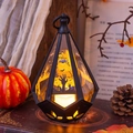 Detalle del farol de Halloween con silueta de cementerio y luz de vela LED cálida dentro - Mano de Fantasma