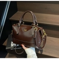 Dettaglio di una borsa Boston in pelle marrone con cuciture bianche e finiture dorate - caffè