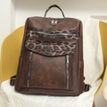 Detail of leopard print stitching and silver zippers on a brown leather backpack - Brown