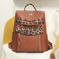 Detail view of brown faux leather backpack featuring leopard print accents and silver zippers - Brown
