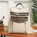 Detail of a beige leather leopard print backpack featuring silver zippers on a wooden table - Off White