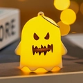 Glowing yellow Halloween ghost pendant with a metal ring and warm bokeh background - Winking Ghost (B)