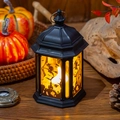 Detail van zwarte Halloween-LED-lantaarn met heksensilhouetten op een houten tafelblad - Heks