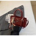 Detail of burgundy glossy leather bucket bag with metallic buckle and tennis racket charm - With Pendant / Red
