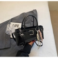 Detalle de un bolso tipo cubo en cuero negro brillante con hebilla y colgante de cuerda rosa - Con Colgante / Negro